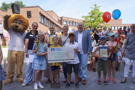 Lions-Maskottchen Leo, Lions-Präsidentin Dr. Lisa Huemke und Bürgermeister Thomas Beckmann überreichen den Gewinnerinnen und Gewinnern des Bücherlöwen Cups im Beisein ihrer Lehrerinnen Urkunde, Pokal und einen Scheck über 750 Euro der VR Bank in Holstein 